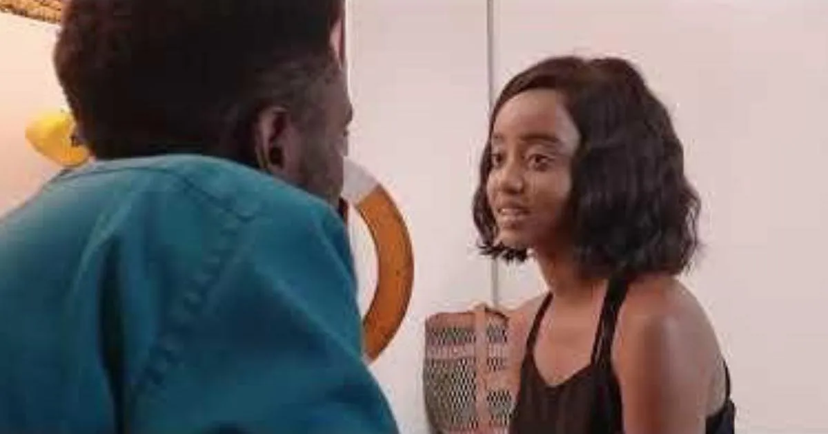 A young woman with a bob haircut talking to a man in a teal shirt